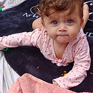Ziya joined the competition — help win amazing prizes! baby, child, blue_eyes, curly_hair, blanket, towel, outdoor, grass, clothing, portrait, face, expression, laying_down, cute, infant, person, skin, pink, soft, young