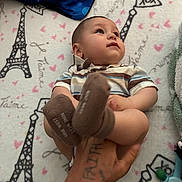 Elias is registered to the contest to win money with this photo: baby, infant, child, hand, tattoo, striped_shirt, brown_socks, blanket, eiffel_tower, hearts, toy, floor, curious, content, indoor, soft_texture, colorful, person, cute, closeup