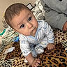 Elias is registered to the contest to win money with this photo: baby, infant, crawling, onesie, animal_print, blanket, bed, person, sleeve, hand, indoor, cute, curious, pattern, leopard_print, zebra_print, soft_toys, cozy, child, portrait