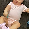 Raniah is registered to the contest to win money with this photo: baby, child, infant, sitting, carpet, pink_outfit, romper, socks, ruffles, smiling, face, portrait, indoors, home, floor, casual, cute, relaxed, playful, photography