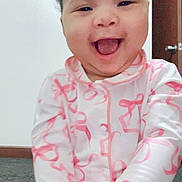 Raniah is registered to the contest to win money with this photo: baby, child, smiling, laughing, pajamas, pink, white, carpet, indoor, door, wall, happy, cute, portrait, sitting, infant, young_child, joyful, hands, face