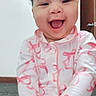 baby, child, smiling, laughing, pajamas, pink, white, carpet, indoor, door, wall, happy, cute, portrait, sitting, infant, young_child, joyful, hands, face