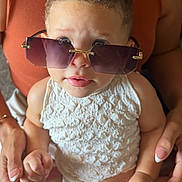 Aliyah Olivia is registered to the contest to win money with this photo: baby, child, infant, portrait, sunglasses, fashion, glamorous, smiling, face, eyes, curly_hair, white_outfit, sleeveless, adult_hands, holding, seated, indoor, close_up, photography, cute