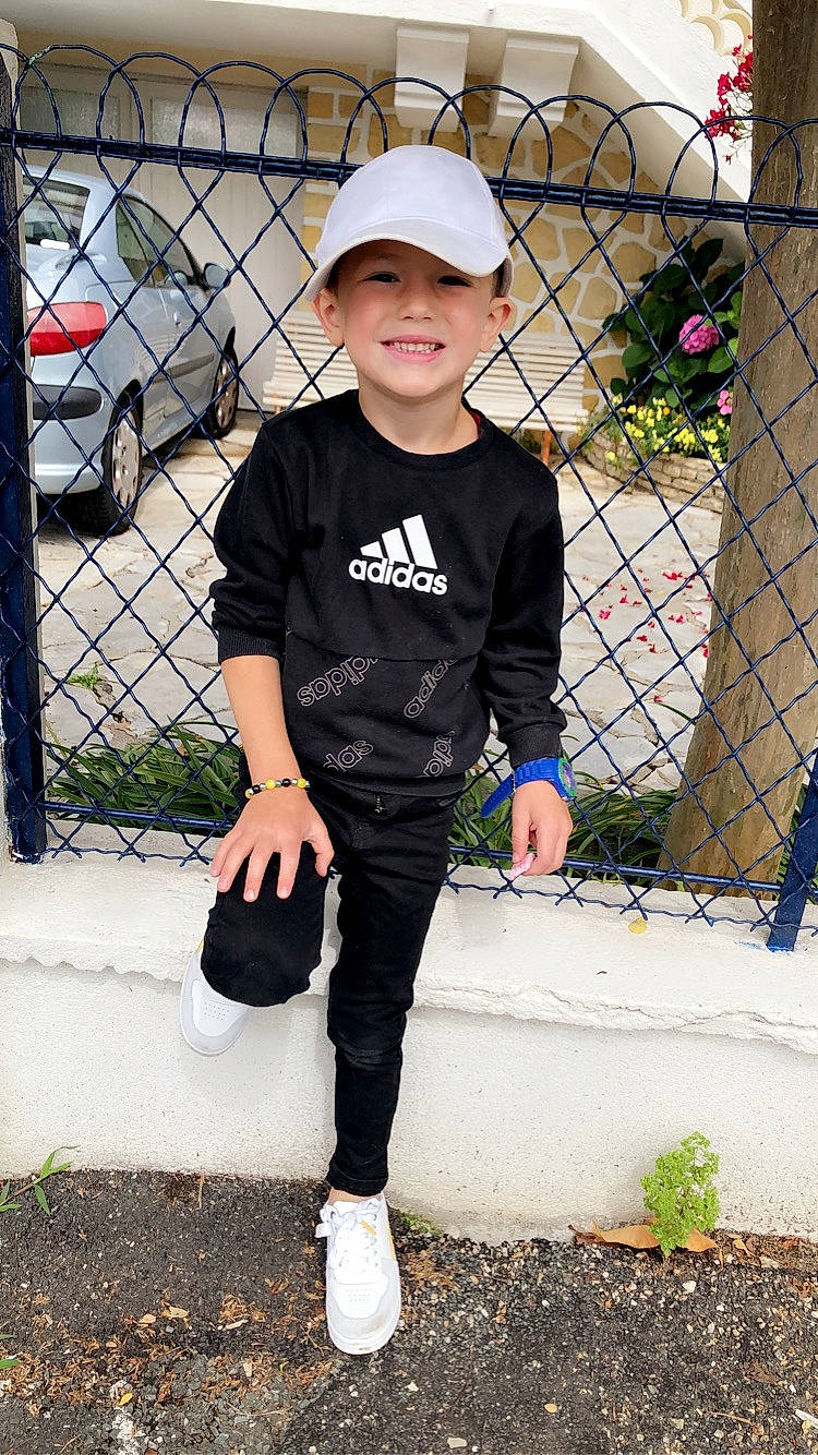 Antonin participe au concours pour gagner de l'argent avec cette photo : baseball_cap, black, cap, car, fence, footwear, hat, headwear, helmet, joy, knee, mesh, person, plant, shoe, sleeve, sneakers, street_fashion, tire, toddler