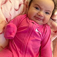 Klaritie is registered to the contest to win money with this photo: baby, infant, child, smiling, portrait, close_up, pink_outfit, onesie, blanket, bedding, lying_down, indoor, face, eyes, hair, happy, cute, plush_fabric, textured_clothing, photograph