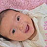 Klaritie is registered to the contest to win money with this photo: baby, infant, child, face, portrait, smiling, happy, lying_down, blanket, pink, white_clothing, onesie, indoor, close_up, brown_hair, eyes, mouth, cozy, textile, photography