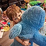 child, toddler, baby, siblings, teddy_bear, stuffed_animal, blue, hugging, playroom, toys, smiling, portrait, indoor, home, messy_room, floor, baby_doll, clothing, family, cuddling