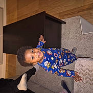 Davi Mendes participe au concours pour gagner de l'argent avec cette photo : child, toddler, pajamas, smiling, indoor, carpet, coffee_table, ottoman, wooden_floor, window, reflection, person, socks, furniture, home, happy, standing, casual, cozy, colorful_clothing