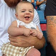 Joseph participe au concours pour gagner de l'argent avec cette photo : baby, man, beard, smile, people, crowd, spectators, seated, shirt, tattoo, shorts, holding, happy, outdoor, event, portrait, person, face, skin, clothing