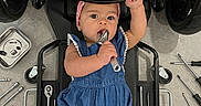 Brittany joined the competition — help win amazing prizes! baby, blue_romper, child, curious, cute, equipment, expression, floor, grip, headwear, indoors, infant, lying_down, mechanic_creeper, pink_headband, playing, small_person, tools, workshop, wrench