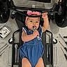 baby, infant, blue_romper, pink_headband, wrench, tools, mechanic_creeper, floor, cute, child, playing, curious, workshop, equipment, grip, lying_down, headwear, expression, small_person, indoors