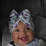 baby, smiling, child, headwear, bow, car_seat, seatbelt, happy, infant, clothing, portrait, cute, indoor, closeup, toddler, fabric, face, person, seat, sitting