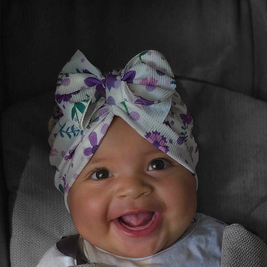 Rawane a rejoint le concours — aidez-le/la à gagner de superbes lots ! baby, bow, car_seat, child, closeup, clothing, cute, fabric, face, happy, headwear, indoor, infant, person, portrait, seat, seatbelt, sitting, smiling, toddler
