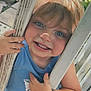 Kingston is registered to the contest to win money with this photo: child, toddler, smiling, blue_shirt, outdoor, wooden_bars, face, hands, sunlight, grass, playful, freckles, blonde_hair, portrait, close_up, happy, person, summer, daylight, cute