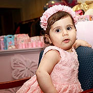 Mariana is registered to the contest to win money with this photo: baby, celebration, chair, child, closeup, curly_hair, cute, decorations, expression, furniture, happy, headband, indoor, party, pink_dress, plush_toy, portrait, seated, soft_lighting, toddler