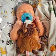 Louis is registered to the contest to win money with this photo: newborn, baby, pacifier, plush_toy, blanket, sleeping, indoor, cute, infant, child, cozy, soft_toys, wrapped, resting, peaceful, colorful, sunlight, shadow, bed, comfort