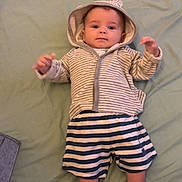 Elio participe au concours pour gagner de l'argent avec cette photo : baby, infant, child, hoodie, striped_clothing, shorts, socks, bed, blanket, floor_tiles, person, indoors, cute, laying_down, looking_at_camera, young, small, comfortable, casual_clothing, resting
