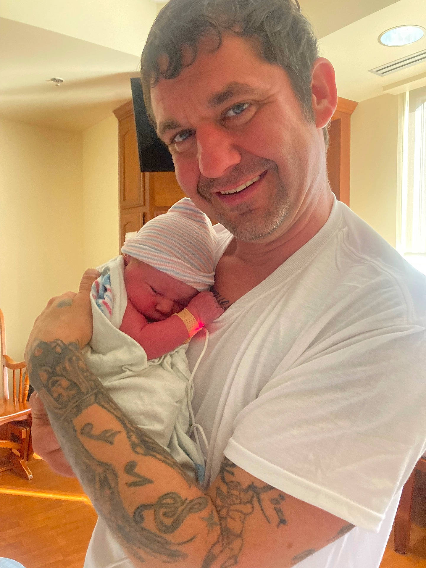 accessories, adult, baby, chair, clothing, computerhardware, face, furniture, glasses, glove, head, male, man, newborn, person, photography, portrait, skin, t_shirt, tattoo