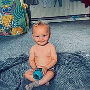 Diego is registered to the contest to win money with this photo: baby, child, smile, sitting, blanket, sippy_cup, indoor, carpet, toy, laundry, window, curtains, sock, playtime, happy, home, radiator, clothing, floor, person