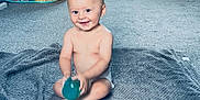 Diego is registered to the contest to win money with this photo: baby, blanket, carpet, child, curtains, cute, diaper, floor, happy, home, indoor, infant, laundry, living_room, person, play_tent, smiling, sock, toy, window