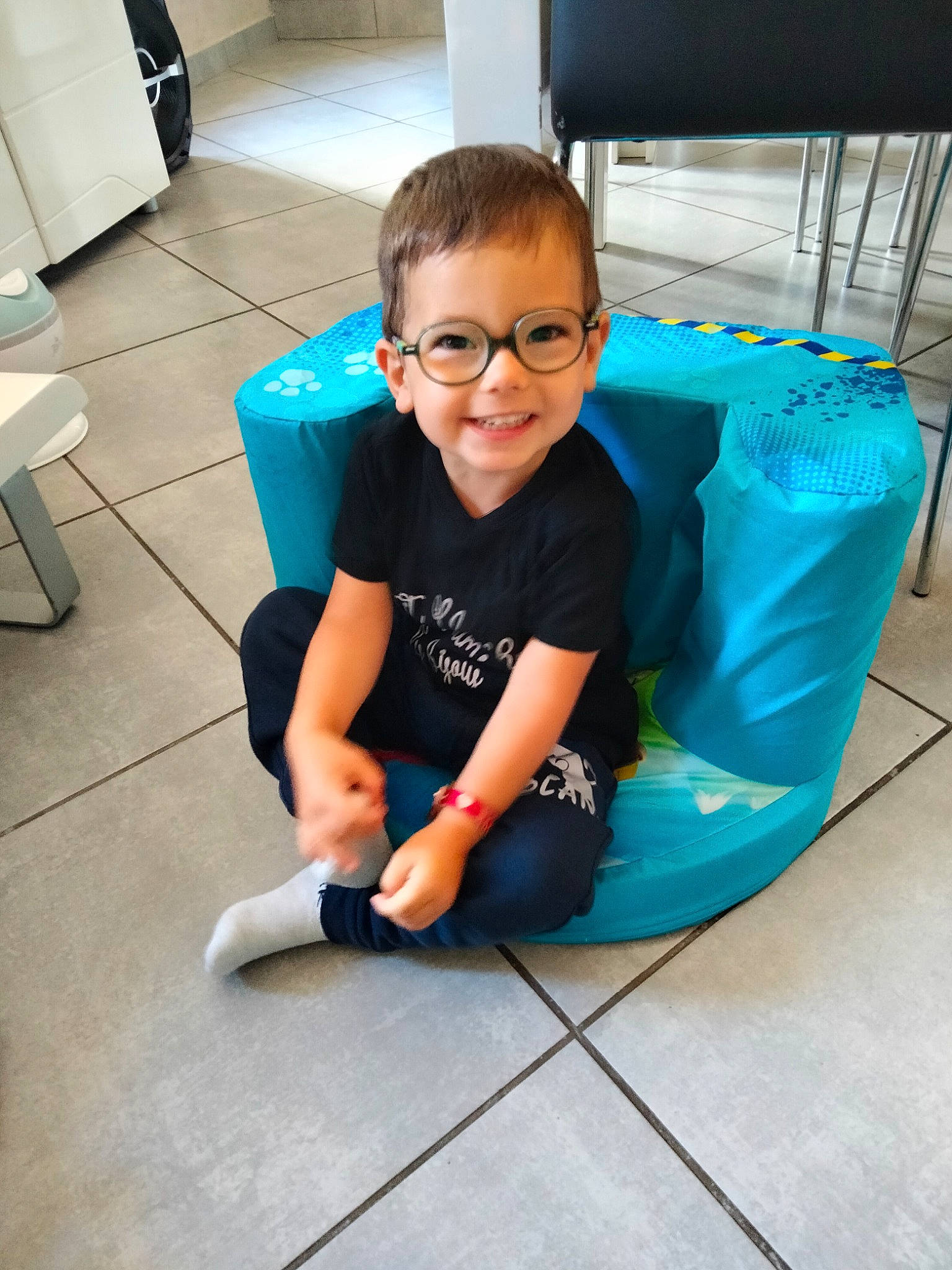 Nolan participe au concours pour gagner de l'argent avec cette photo : comfort, elbow, eyewear, floor, flooring, fun, glasses, hairstyle, happy, human_leg, joint, joy, knee, leg, leisure, person, shorts, sleeve, smile, sneakers