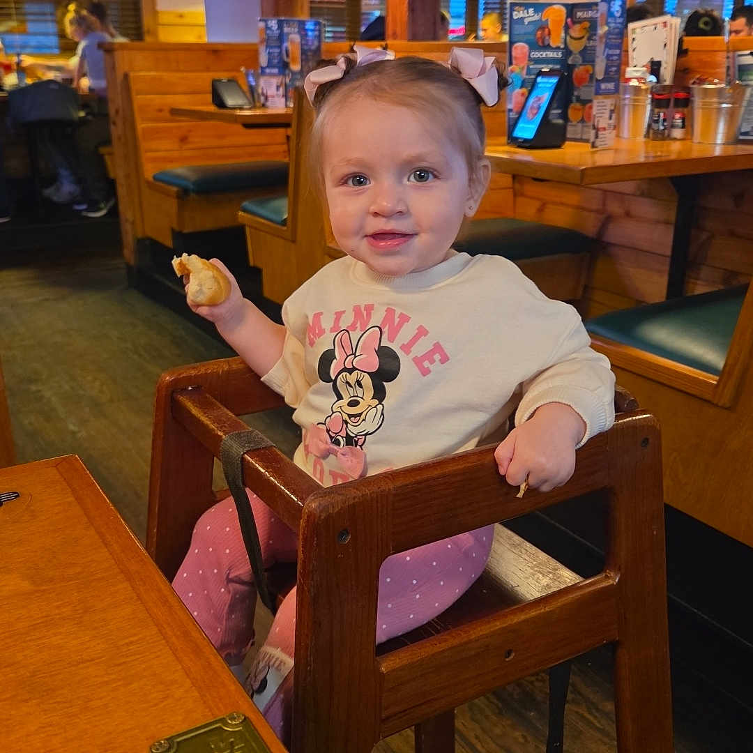Kelianys Ross is registered to the contest to win money with this photo: toddler, child, baby, restaurant, high_chair, sitting, smiling, snack, food, minnie_mouse, bow, shirt, polka_dots, wooden_furniture, pendant_lights, booth, indoor, dining, portrait, happy
