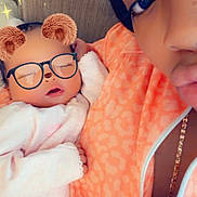 China is registered to the contest to win money with this photo: adult, baby, bear_ears_filter, casual, chain_necklace, child, closeup, couch, cozy, face_filter, glasses_filter, hand, indoor, orange_jacket, peaceful, person, portrait, resting, sleeping, zipper