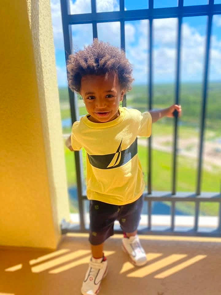 Issac is registered to the contest to win money with this photo: child, electric_blue, fence, flooring, fun, glass, happy, human_leg, knee, leisure, person, play, recreation, reflection, shorts, sky, sportswear, standing, t_shirt, thigh