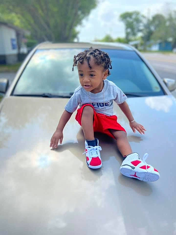 Issac is registered to the contest to win money with this photo: automotive_design, automotive_exterior, automotive_lighting, bumper, car, child, dress, electric_blue, hood, leisure, motor_vehicle, person, recreation, t_shirt, tints_and_shades, toddler, tree, vehicle, vehicle_door, windscreen_wiper