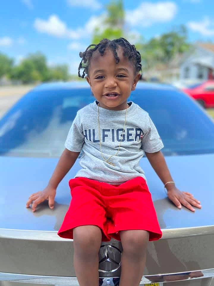 Issac is registered to the contest to win money with this photo: automotive_design, automotive_exterior, automotive_lighting, blue, bumper, car, cloud, happy, hood, leisure, motor_vehicle, person, shorts, sky, street_fashion, summer, t_shirt, thigh, toddler, vehicle