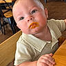 baby, child, high_chair, food, face, curious, indoor, wooden_furniture, table, restaurant, orange_food, clothing, short_sleeve, person, cute, portrait, seat, cafe, plush_cheeks, dining