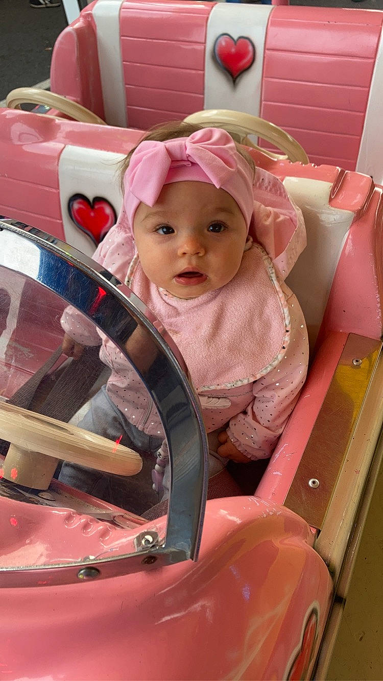 Nalya a rejoint le concours — aidez-le/la à gagner de superbes lots ! auto_part, automotive_design, automotive_exterior, baby, baby_carriage, baby_products, baby_safety, baby_toddler_clothing, child, comfort, family_car, fun, headwear, magenta, motor_vehicle, person, pink, sitting, toddler, vehicle