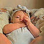 Sara is registered to the contest to win money with this photo: baby, infant, headband, hand, face, skin, eyes, lying_down, clothing, blanket, soft, cute, indoors, portrait, child, newborn, resting, comfort, warm_light, closeup