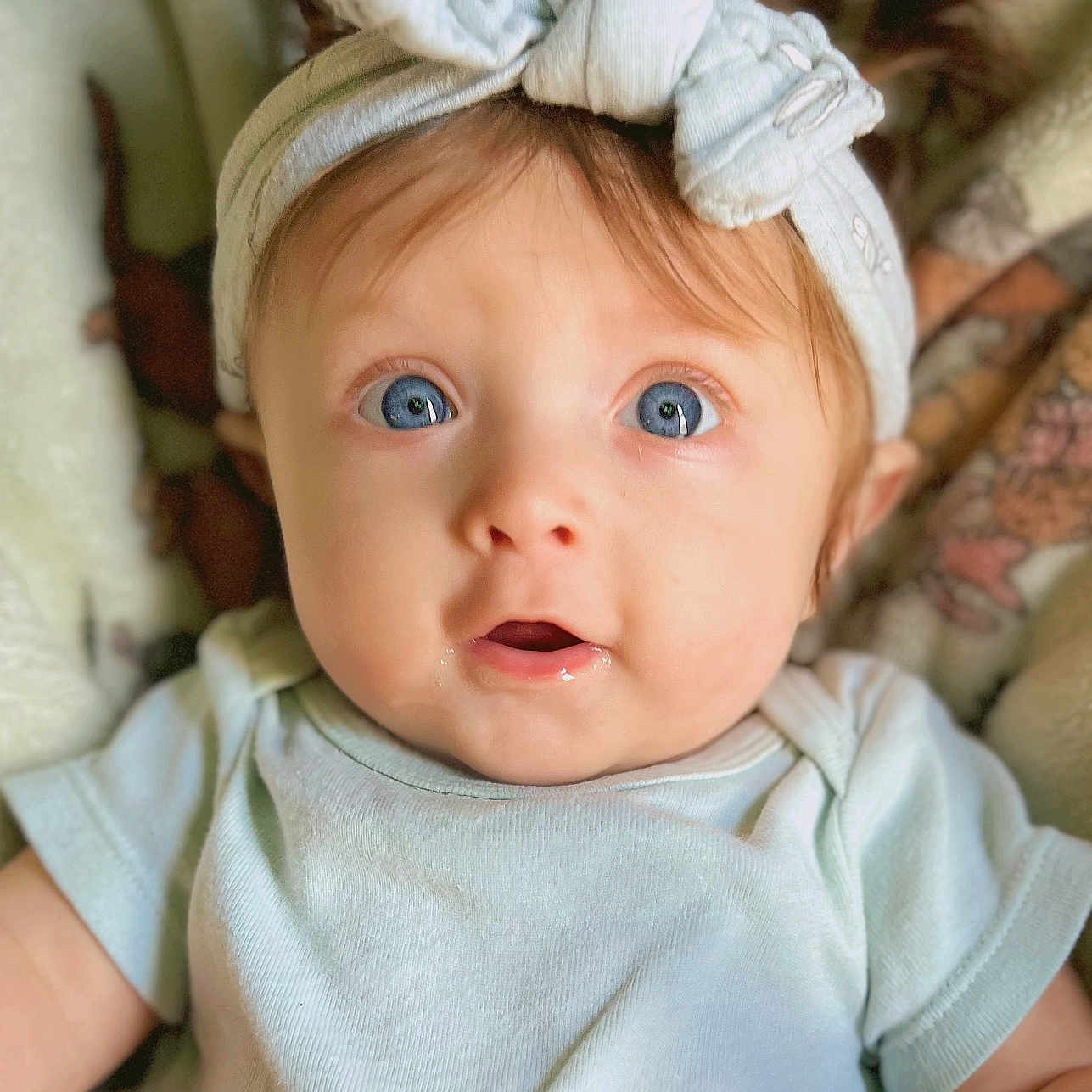 Sara joined the competition — help win amazing prizes! apparel, baby, blanket, blue_eyes, child, clothing, cute, drool, expression, face, headband, headwear, indoors, infant, person, pigtails, portrait, skin, soft, young