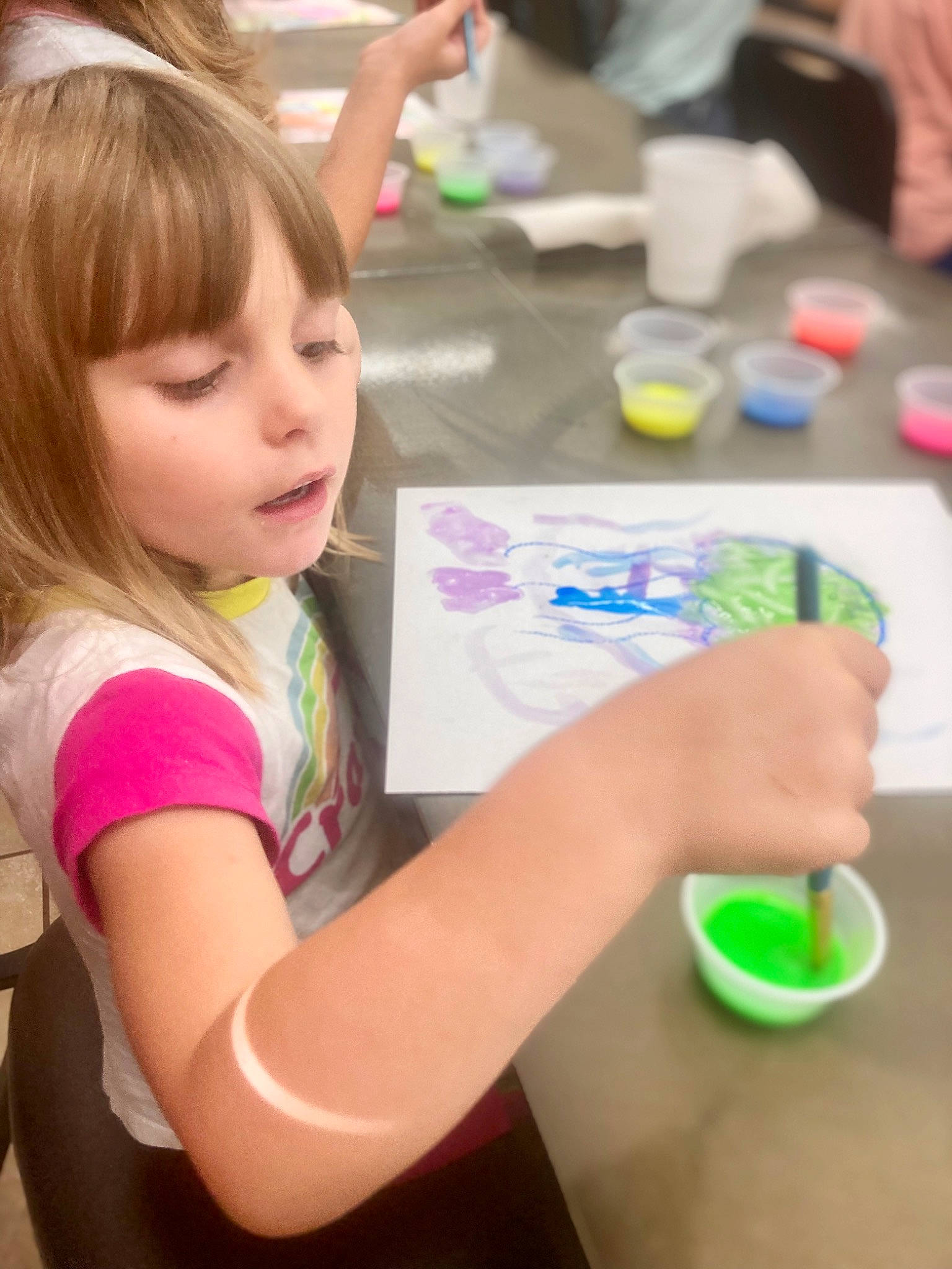 Carolyn is registered to the contest to win money with this photo: adaptation, arm, chair, child, child_art, event, finger, fun, hand, happy, leisure, nail, paint, person, play, room, sharing, t_shirt, table, toddler