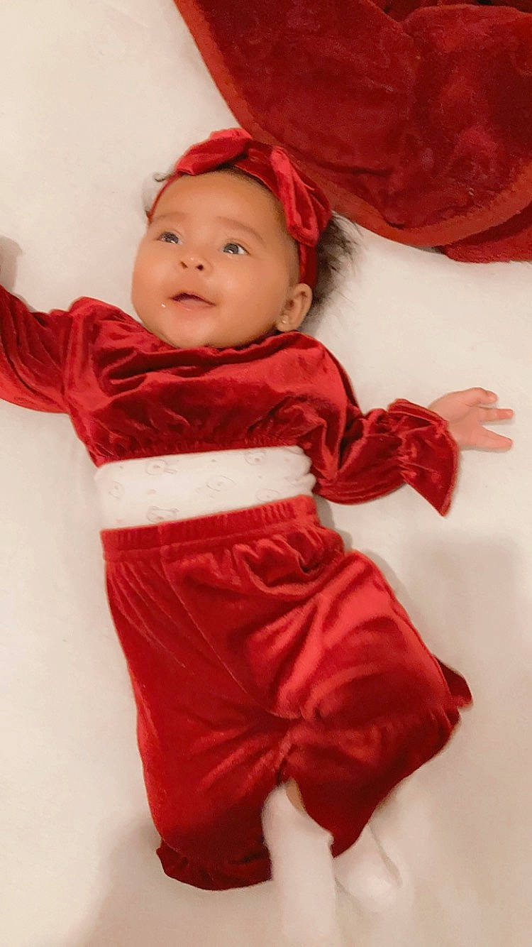 Talhïa a rejoint le concours — aidez-le/la à gagner de superbes lots ! baby, baby_toddler_clothing, cheek, child, collar, comfort, event, face, formal_wear, fur, happy, headwear, outerwear, person, pink, red, sitting, skin, sleeve, smile