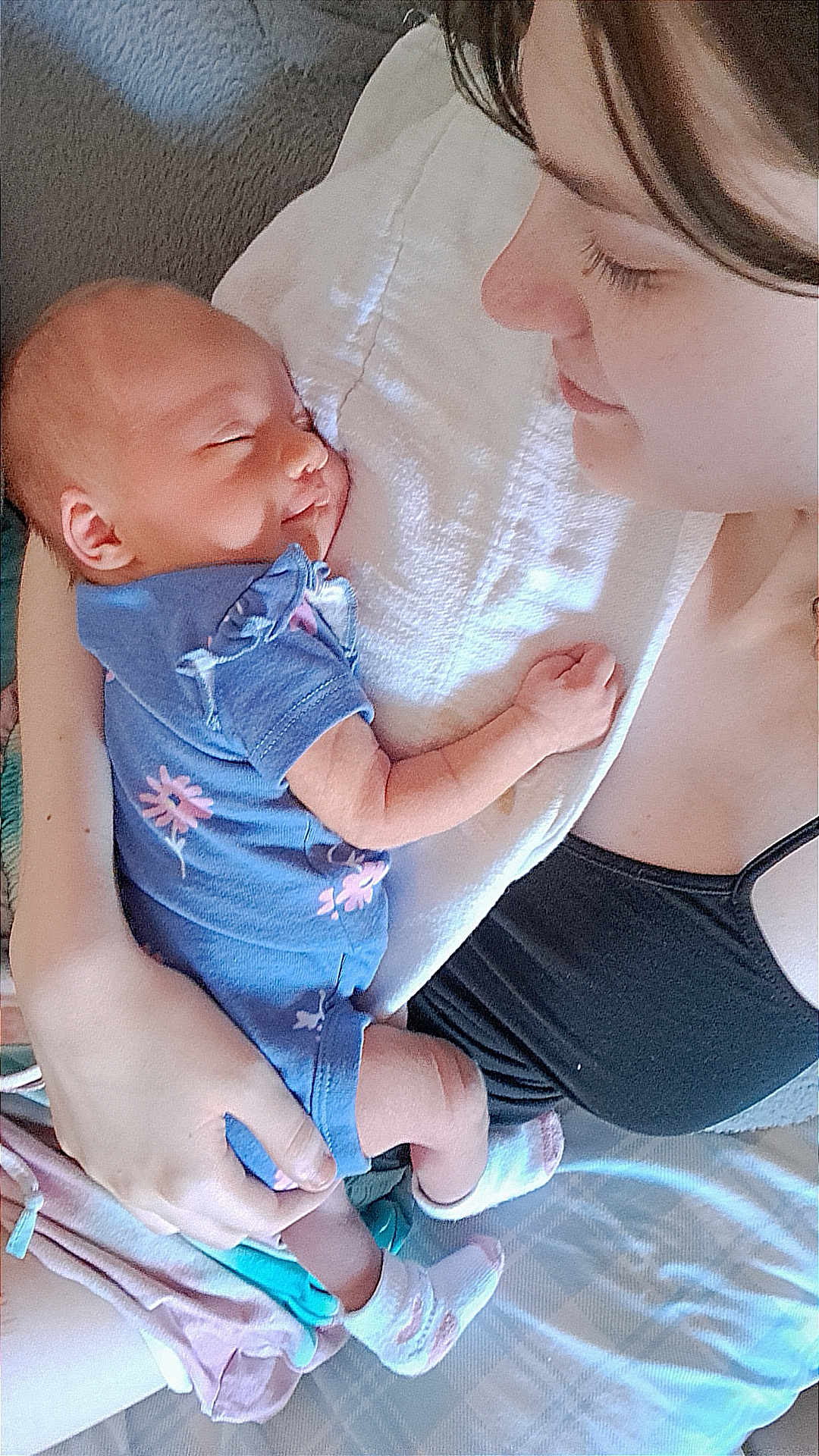 Astreya joined the competition — help win amazing prizes! baby, infant, woman, sleeping, holding, blue_onesie, floral_pattern, white_cloth, smiling, face, arm, hand, socks, bed, blanket, closeup, skin, person, tender_moment, indoor