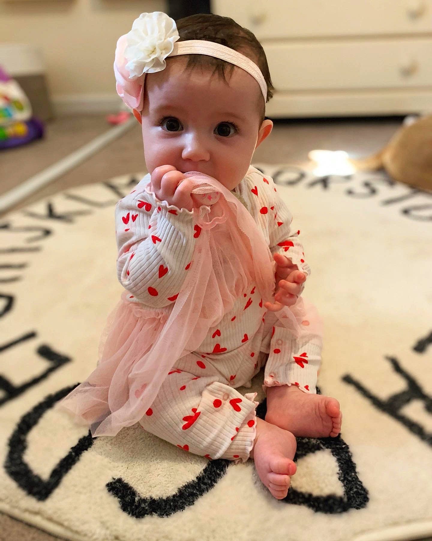 Lylah is registered to the contest to win money with this photo: baby, baby_toddler_clothing, cap, carmine, cheek, child, facial_expression, finger, flooring, foot, fun, happy, kneeling, linens, pattern, person, pink, sitting, skin, sleeve