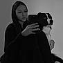 woman, dog, black_and_white, selfie, phone, sitting, indoor, pet, long_hair, casual_clothing, calm, portrait, fur, friendship, reflection, monochrome, relaxed, companion, floor, blanket