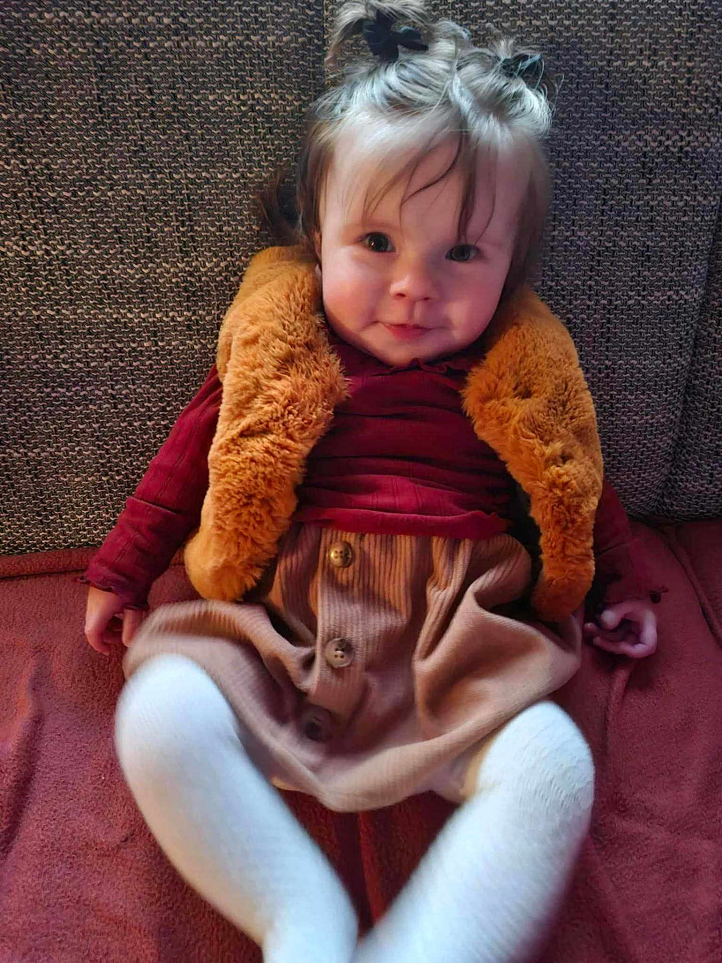 Ambre participe au concours pour gagner de l'argent avec cette photo : toddler, child, smiling, sitting, couch, fuzzy_vest, pony_tail, white_tights, brown_skirt, red_top, indoors, portrait, happy, face, person, clothing, fabric, home, cozy, cute