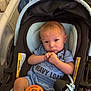 Adan is registered to the contest to win money with this photo: baby, infant, car_seat, blue_outfit, pacifier, bottle_cap, serious_expression, child, indoor, seat_belt, warning_label, person, young_child, cute, small_hands, head, face, clothing, transport, sitting