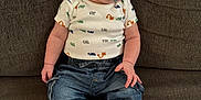 Jagger is registered to the contest to win money with this photo: baby, infant, pacifier, onesie, denim_pants, couch, smile, happy, child, sitting, indoor, cute, clothing, foot, human, face, expression, comfort, relaxation, portrait