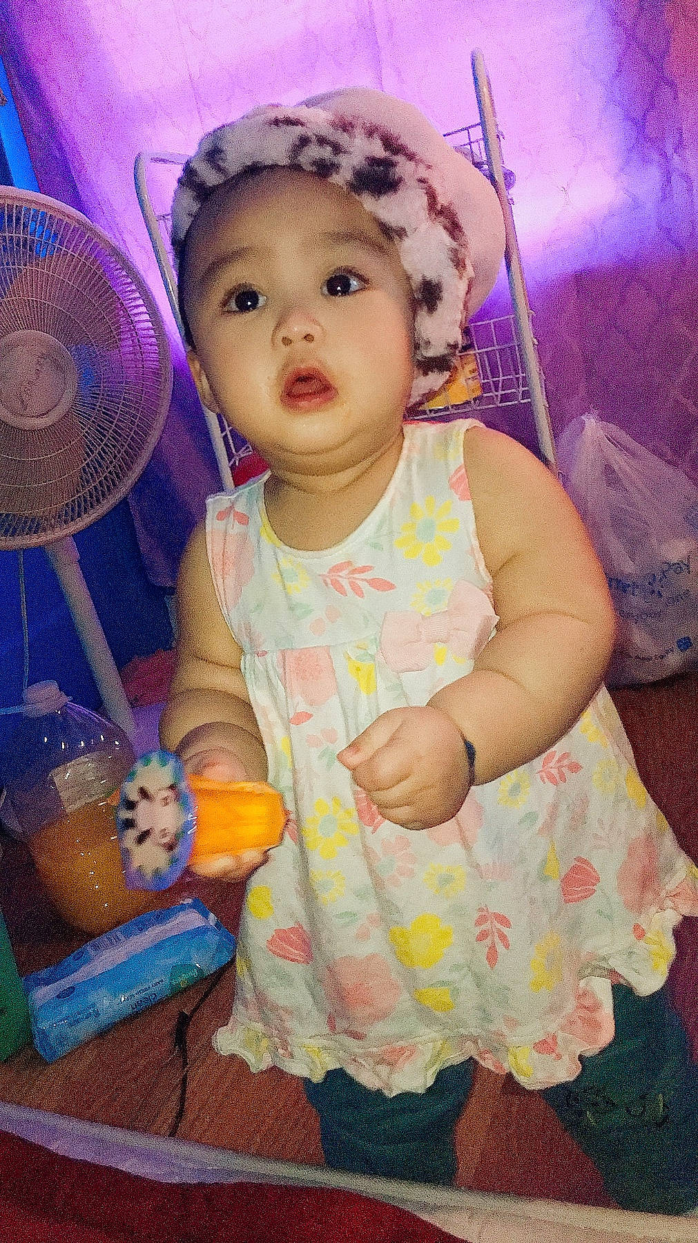 Nora is registered to the contest to win money with this photo: baby, baby_products, baby_toddler_clothing, bonnet, child, cocktail, day_dress, electric_fan, headwear, juice, lavender, mechanical_fan, person, pink, purple, surprise, toddler, violet