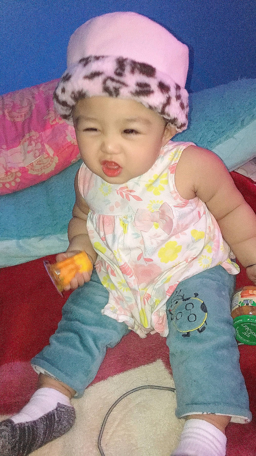 Nora is registered to the contest to win money with this photo: baby, baby_products, baby_toddler_clothing, beanie, bonnet, cheek, child, costume_accessory, hair_accessory, headband, headpiece, headwear, knit_cap, linens, mouth, nose, person, pink, sock, textile