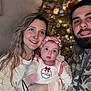 family, baby, woman, man, smile, portrait, indoor, holiday, christmas_tree, headband, beard, sweater, warm_clothing, happy, togetherness, celebration, blurred_background, face, people, festive
