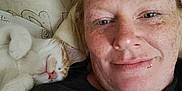 Pumpkin is registered to the contest to win money with this photo: person, cat, sleeping_cat, face, freckles, lip_ring, sunglasses, pillow, couch, indoor, closeup, relaxed, snuggling, pet, white_cat, orange_cat, resting, casual, home, comfort