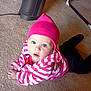 baby, child, pink_hat, striped_jacket, carpet, indoor, heater, floor, person, blue_eyes, clothing, crawling, cute, young_child, infant, headwear, homedecor, furniture, warm_clothing, expression