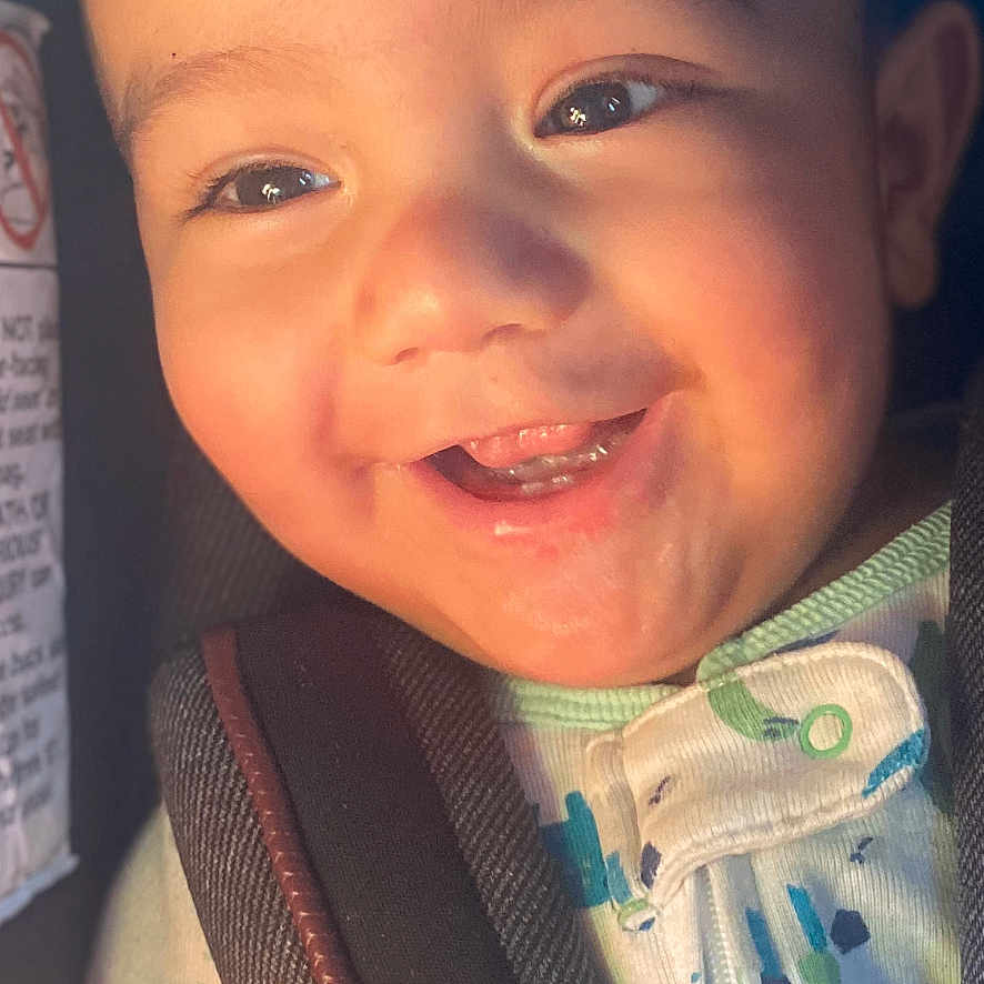 Lucas is registered to the contest to win money with this photo: accessories, baby, babylaughing, belt, bodypart, clothing, coat, cushion, face, happy, head, homedecor, jacket, laughing, mouth, person, photography, portrait, smile, teeth