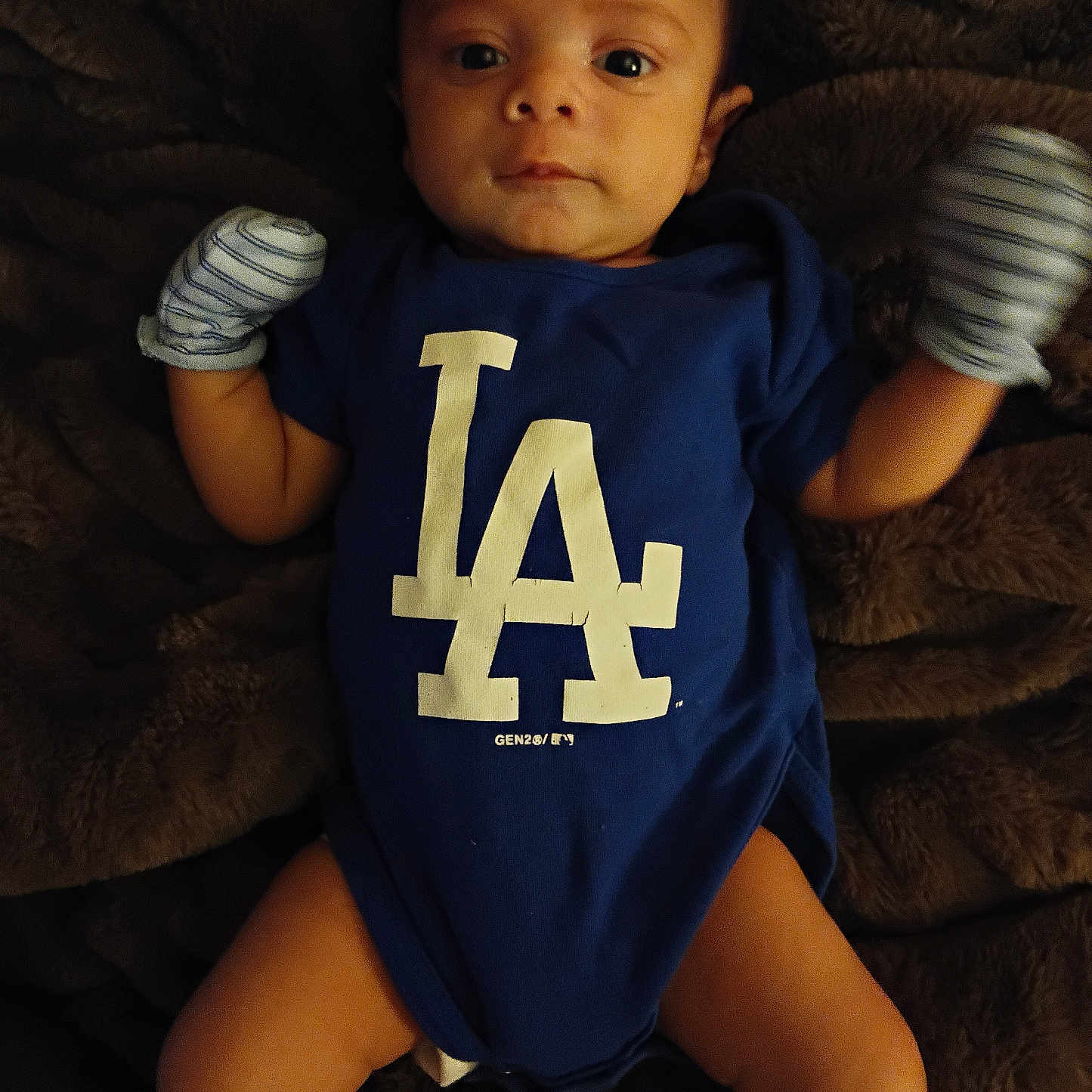 Akyrus is registered to the contest to win money with this photo: baby, infant, blue_onesie, mittens, blanket, lying_down, face, eyes, expression, clothing, young_child, indoor, portrait, cute, newborn, skin, head, hands, legs, babywearing