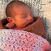 Nova is registered to the contest to win money with this photo: newborn, baby, sleeping, blanket, crocheted_blanket, brown_blanket, face, head, hand, patterned_cushion, zigzag_pattern, soft_texture, cozy, indoor, closeup, resting, peaceful, infant, wrapped, portrait